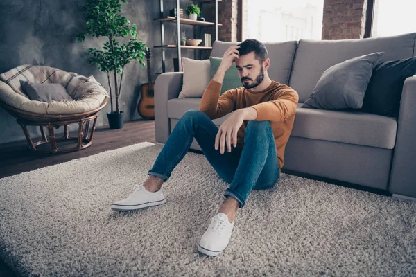 Retrato de frustrado elegante moda hipster tacto dedos de la cabeza mano palma sentarse suéter naranja jeans vaqueros zapatillas de deporte blanco apartamento grande desesperación interior — Foto de Stock