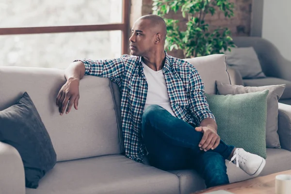 Profile side view photo of lovely charming attractive millennial sit divan peaceful gorgeous dressed denim jeans checked shirt apartment sneakers have thoughts — Stock Photo, Image