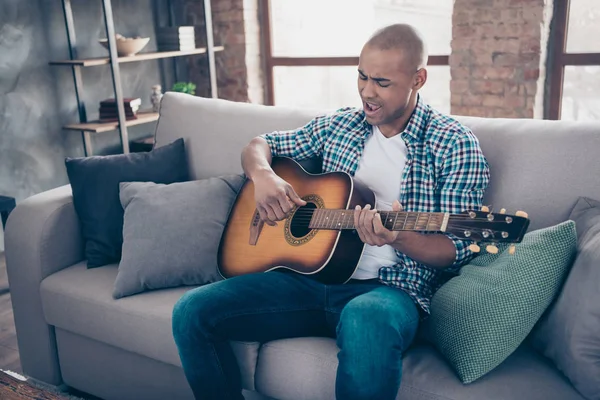 Portarit de concentrado encantador millennial celebrar mano instrumento musical voz ensayo preparar concierto casual camisa a cuadros vaqueros sentarse diván apartamento habitación — Foto de Stock