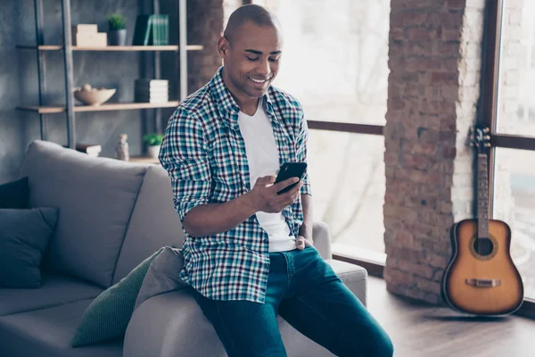 Retrato de positivo encantador alegre milenial de la mano la tecnología moderna leer tiempo libre noticias stand habitación apartamento comprobado camisa vaqueros a cuadros — Foto de Stock