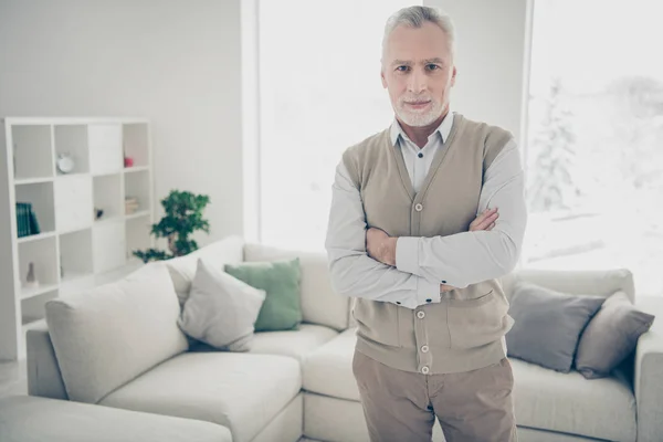 De cerca foto increíble manager él sus brazos de hombre de edad cruzados jefe mandona mirada confiado en sí mismo usar camisa blanca chaleco pantalones de pie cerca de la comodidad acogedora diván brillante casa plana sala de estar en el interior —  Fotos de Stock