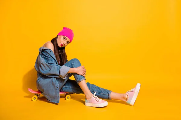 Comprimento total perfil lateral tamanho do corpo foto bonita ela sua senhora fim de semana férias desportivo tempo livre sentado próprio skate bordo desgaste casual jeans jeans jaqueta sapatos rosa chapéu isolado amarelo fundo vívido — Fotografia de Stock