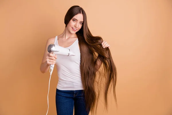 Close up foto bello stupefacente lei lei signora braccia mani tenere molto lungo capelli arricciacapelli asciugatura attrezzature godere di facile semplice processo usura casual bianco serbatoio-top jeans denim isolato pastello beige sfondo — Foto Stock