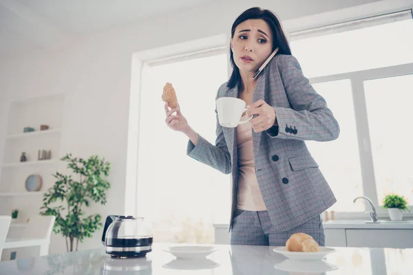 Zavřít fotografii krásně unavenou, ta její dáma šálek horkého nápojového stolu croissant ruční rameno pozdní práce rychle mluvit říkat říkat telefon formální-nosit šeřivý plánek kostým světlá bílá kuchyně uvnitř — Stock fotografie