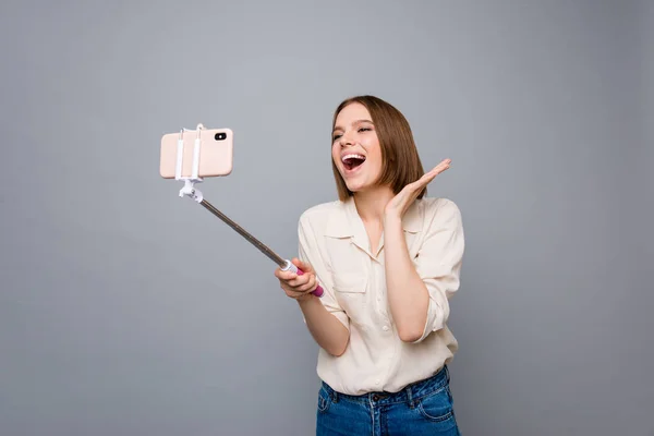 Close up photo amazing beautiful she her lady hold hands arms metal phone stick overjoyed crazy funky funny speak tell skype foreign friends wear casual white shirt isolated grey background — Foto de Stock