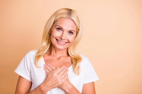 Närbild foto av fantastiska åldrad Lady händer bröstet överlycklig ganska Toothy slitage vit casual t-shirt isolerad pastell beige bakgrund — Stockfoto