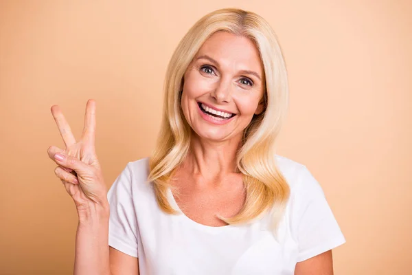 Närbild foto av åldrig Lady hand fingrar Visa v-Sign säga Hej vänner bära vit casual t-shirt isolerad pastell beige bakgrund — Stockfoto