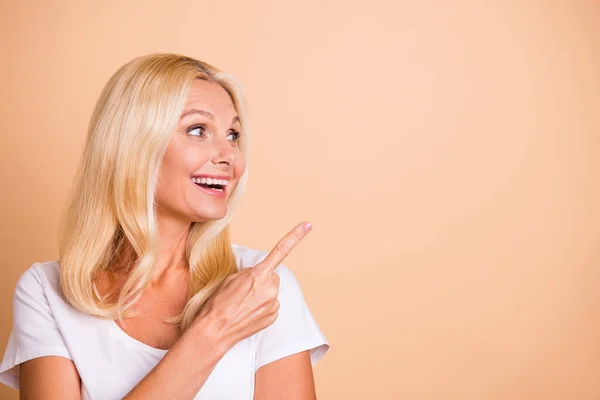 Foto de la mano de la señora de mediana edad indican espacio vacío precio fresco nuevo producto desgaste blanco casual camiseta aislado pastel beige fondo — Foto de Stock