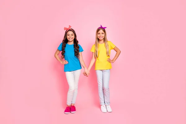 Full length body size view of two nice-looking attractive charming lovely friendly cheerful pre-teen girls holding hands isolated on pink pastel background — стоковое фото
