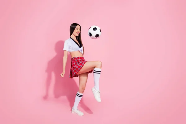 Ganzkörper-Seite Foto von coolen Dame Fußballspieler macht erstaunliche Tricks Beine tragen roten kurzen Rock weißen Top isoliert rosa Hintergrund — Stockfoto