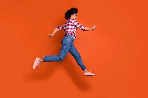 Full längd sida foto av hoppning hög atletisk Lady Run shopping försäljning rabatt slitage Jeans denim byxor pläd skjorta outfit isolerad orange bakgrund — Stockfoto