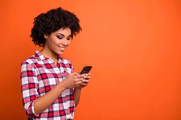 Zavřít boční fotografii atraktivní dámy držet ruce telefon psát čtecí zařízení e-mail tisíciletí nosit neformální Kostlivou Kostlivou košili izolované oranžové pozadí — Stock fotografie
