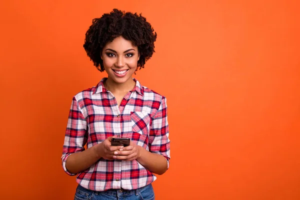 Foto de engraçado bonita senhora segurar as mãos telefone escrita carta e-mail desgaste casual xadrez xadrez camisa isolado laranja brilhante fundo — Fotografia de Stock