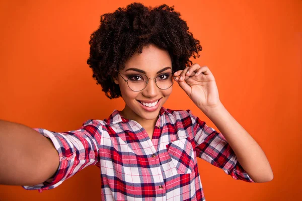 Foto de señora divertida haciendo selfies juguetón agarre mano gafas desgaste especificaciones casual a cuadros camisa aislado naranja brillante fondo — Foto de Stock