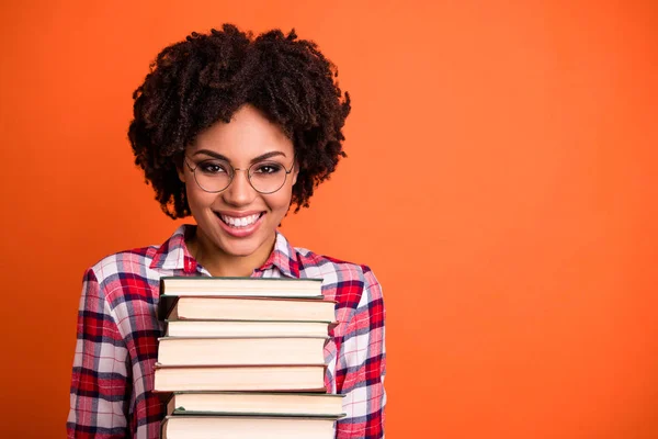 Крупним планом красива позитивна жінка тримає руки багато книг готують екзамен радий повернутися назад до школи зубний одяг з картатими сорочками ізольовані яскраво-помаранчевий фон — стокове фото