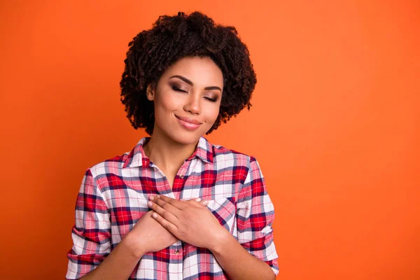 Close-up portrait of her she nice attractive lovable sweet tender winsome cheerful wavy-haired lady in checked shirt folded hands on heart feelings isolated on bright vivid shine orange background — Stock Photo, Image