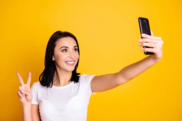 Yakın çekim fotoğraf güzel şaşırtıcı o onun bayan telefon el kolu selfies v-sign sembolü konuşmak konuşmak skype arkadaşlar rahat beyaz t-shirt kot denim izole parlak sarı arka plan giymek demek yapmak — Stok fotoğraf