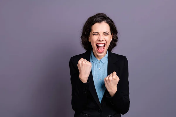 Retrato de encantado divertido funky lady millennial levantar los puños gritar sí ondulado rizado corte de pelo encantador desgaste negro elegante chaqueta aislado gris fondo — Foto de Stock