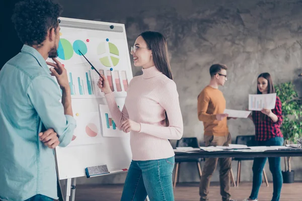 Foto af to positive munter dame fyr har diskussion møde show data taler tale sige fortælle slid pullover sweater jeans denim briller briller look analyse stå interiør loft industrielle - Stock-foto