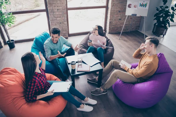 Por encima de la vista de ángulo alto de inteligentes inteligentes alegres pasantes alegres preparando análisis desarrollo carrera compartir ideas consultoría sentado en la silla de la bolsa en la estación de trabajo interior loft industrial — Foto de Stock