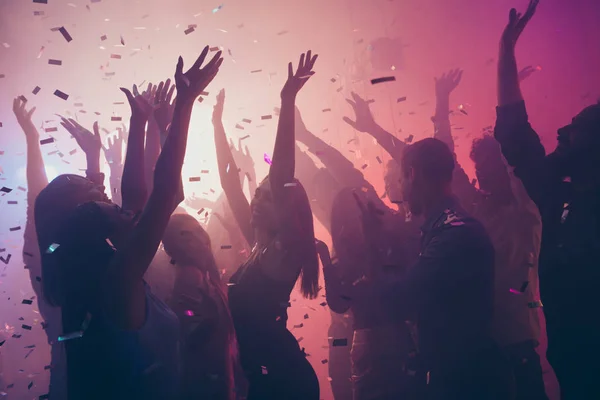 Foto de muitos eventos de aniversário pessoas dançando luzes coloridas confete voando desfrutar de mãos de boate levantadas vestir roupas brilhantes — Fotografia de Stock