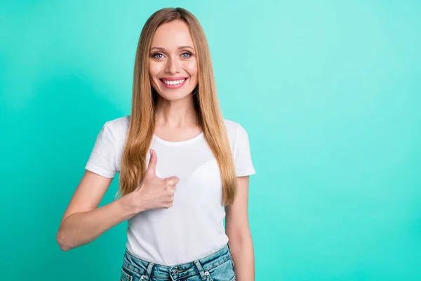 Portret van vrolijke dame tonen duim omhoog glimlachend op camera dragen denim jeans geïsoleerd over Teal Turquoise achtergrond — Stockfoto