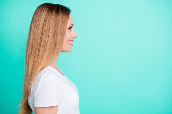 Foto del lado del perfil de una agradable dama que mira sonriente usando una camiseta blanca aislada sobre un fondo azul turquesa — Foto de Stock