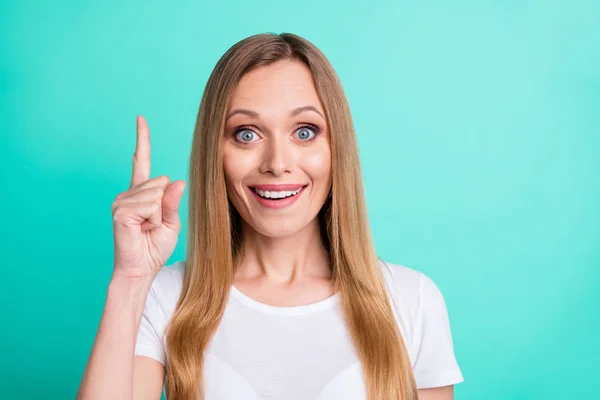 Foto de cerca de una persona divertida asombrada apuntando con el dedo índice hacia arriba usando una camiseta blanca aislada sobre un fondo azul turquesa — Foto de Stock