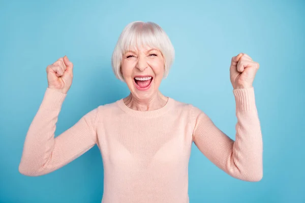 Портрет радостной веселой дамы, поднимающей кулаки и кричащей: Да, в пастельном свитере, изолированном на синем фоне — стоковое фото