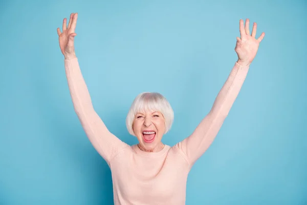 Портрет веселой современной леди, поднимающей руки и кричащей в пастельном свитере на синем фоне — стоковое фото