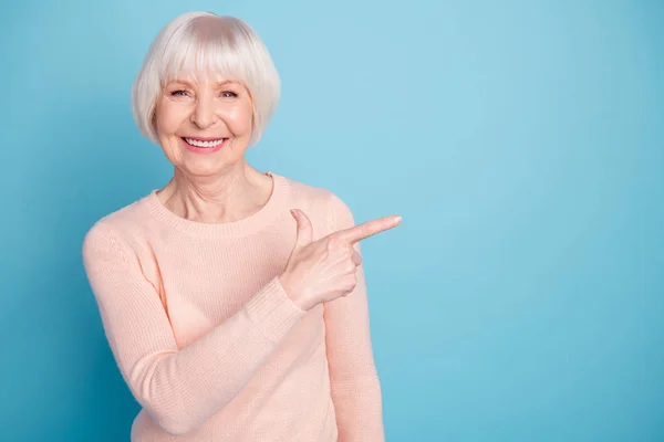 Retrato de senhora bonita apontando para o espaço de cópia sorrindo usando jumper pastel isolado sobre fundo azul — Fotografia de Stock