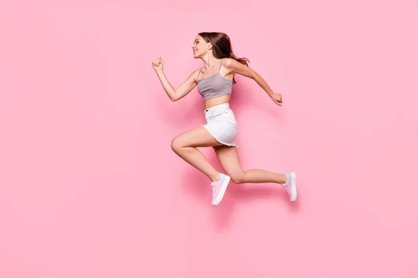 Perfil lado cuerpo completo foto de chica bonita corriendo vistiendo gris camiseta blanca falda aislada sobre fondo rosa —  Fotos de Stock