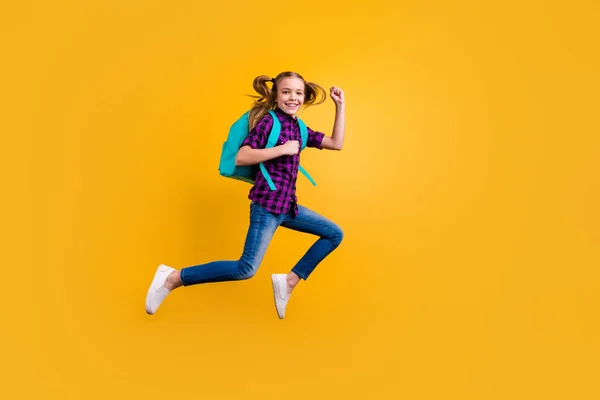 Full length side photo of little pupil jump high glad return school wear casual checkered shirt jeans denim isolated yellow background — Stock Photo, Image