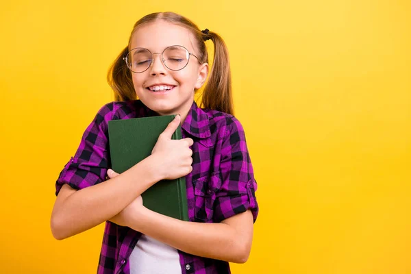 Foto von kleinen Dame Schüler halten Buch in der Nähe der Brust Augen geschlossen genießen letzte Abnutzung Spezifikationen kariertes Hemd isoliert gelb Hintergrund — Stockfoto