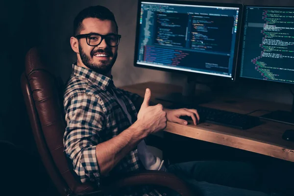 Close up side profile photo handsome he him his guy coder advising web agency thumb up keyboard development outsource IT processing language two monitors table office wear specs formalwear plaid shirt