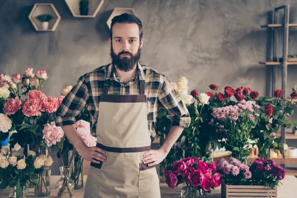 Ritratto del suo bel ragazzo contenuto attraente indossa uniforme camicia a quadri tra peonia diversi grappolo vendita al dettaglio al salone stile cemento industriale all'interno — Foto Stock