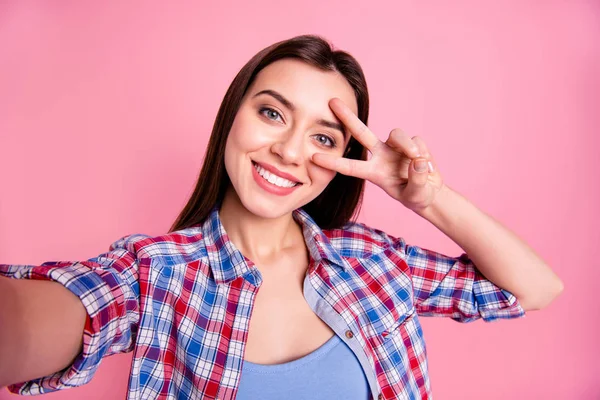 Közelről fotó szép csodálatos lány hölgy, hogy vegye selfies beszélnek mondani Skype barátok rokonok v-jel szimbólum közelében szem Instagram kopás alkalmi kockás kockás ing ruhát izolált rózsaszín háttér — Stock Fotó