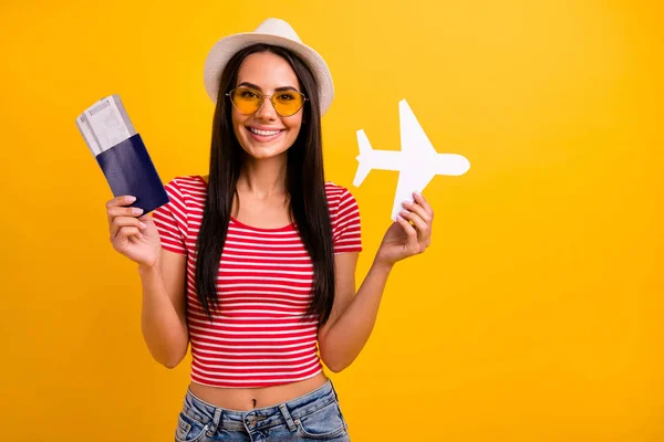 Retrato de agradable estudiante encantadora toma de la mano avión de la tarjeta de papel quiere viajero tour tiene gafas gafas jeans denim sentir contenido descansar relajarse aislado amarillo brillante fondo — Foto de Stock