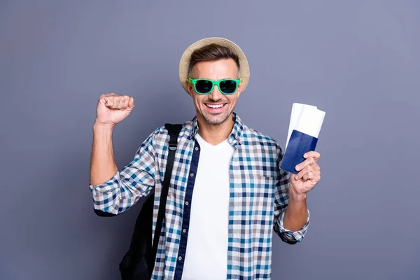 De cerca foto guapo él su hombre brazo mano pasaporte boletos ganado lotería ir gratis en el extranjero país extranjero divertido sombrero bolso usar sol especificaciones casual cuadros camisa a cuadros aislado gris fondo — Foto de Stock