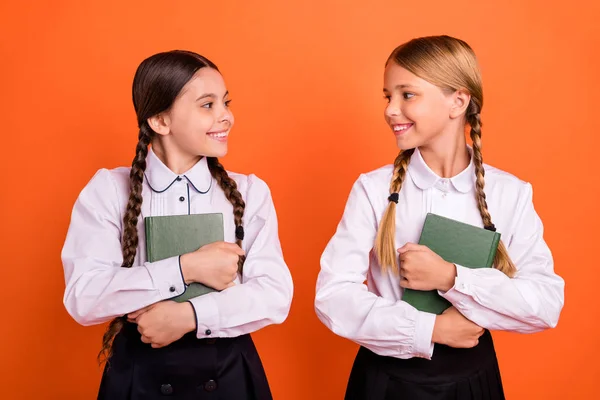 Portrait of two person nice-looking attractive lovely sweet charming cute cheerful pre-teen girls learners holding lesson course materials in hands isolated over bright vivid shine orange background — Stock Photo, Image