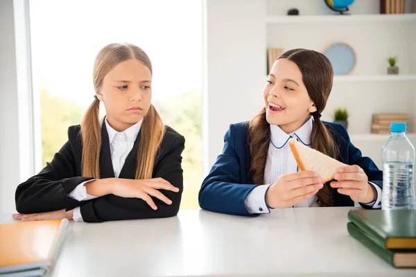 Portrait of two person nice attractive charming cute cheerful funny girls having lunch pause break breakfast want wish tease fresh sandwich one girl offended in light white interior class room indoors — Stock Photo, Image