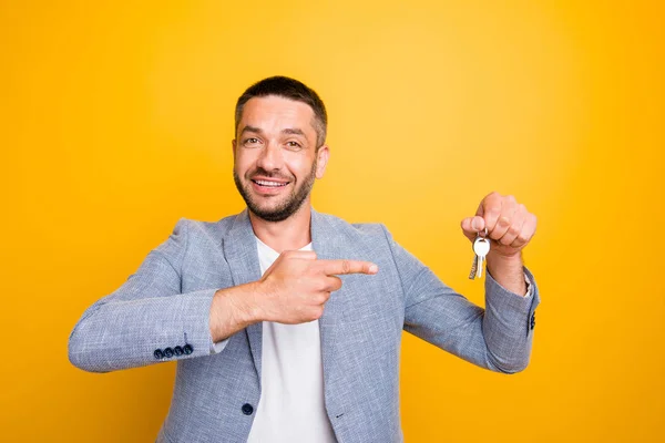 Retrato de su atractivo atractivo chico positivo alegre que sostiene en la mano apuntando a las llaves agente agente de bienes raíces gerente aislado sobre brillante brillante brillo fondo amarillo — Foto de Stock