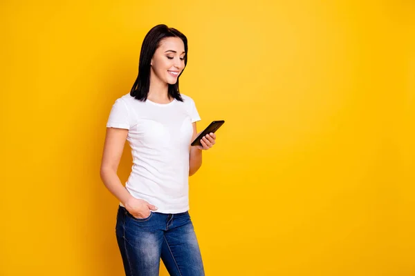 Close up photo beautiful amazing she her lady easy-going reading great good news phone hand arm millennial texting friends wear casual white t-shirt jeans denim isolated bright yellow background — Foto de Stock