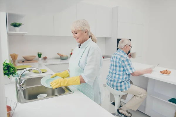 Portrait of nice cute old lady hold hand polishing drying plates wet hands enjoy house work have kitchenwear stand indoors — Stock Photo, Image