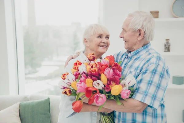 Retrato de ella ella su él dos agradable atractivo alegre alegre dulce tierna gente abuela recibir frescos tulipanes florales felicitaciones saludos primavera en blanco claro interior sala de estar — Foto de Stock