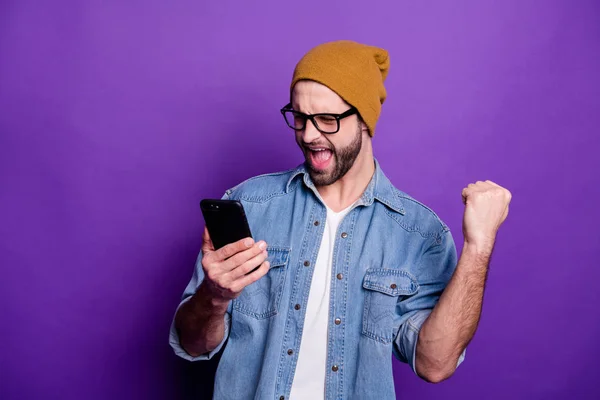 Cool bel ragazzo in possesso di telefono orologio partita di calcio casual denim vestito isolato sfondo viola — Foto Stock