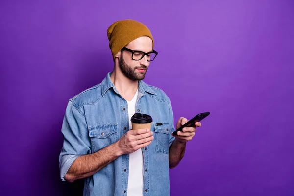 クールなハンサムな男は、電話を飲んでコーヒーカジュアルな衣装孤立した紫色の背景を持っています — ストック写真