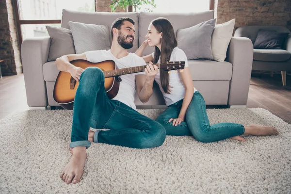 Dos simpáticos atractivos y tiernos alegres alegres y alegres personas positivas que se divierten pasando el día de vacaciones el fin de semana sentado en el suelo tocando canciones melodía en casa apartamento en interiores — Foto de Stock