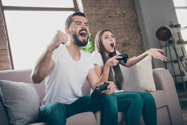 Foto di divertente coppia seduta divano in casa a giocare ai videogiochi eccitati da vincite e perdite inaspettate — Foto Stock