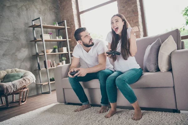 Foto de sofá sentado par engraçado dentro de casa jogando jogos de vídeo animado por vitória inesperada — Fotografia de Stock